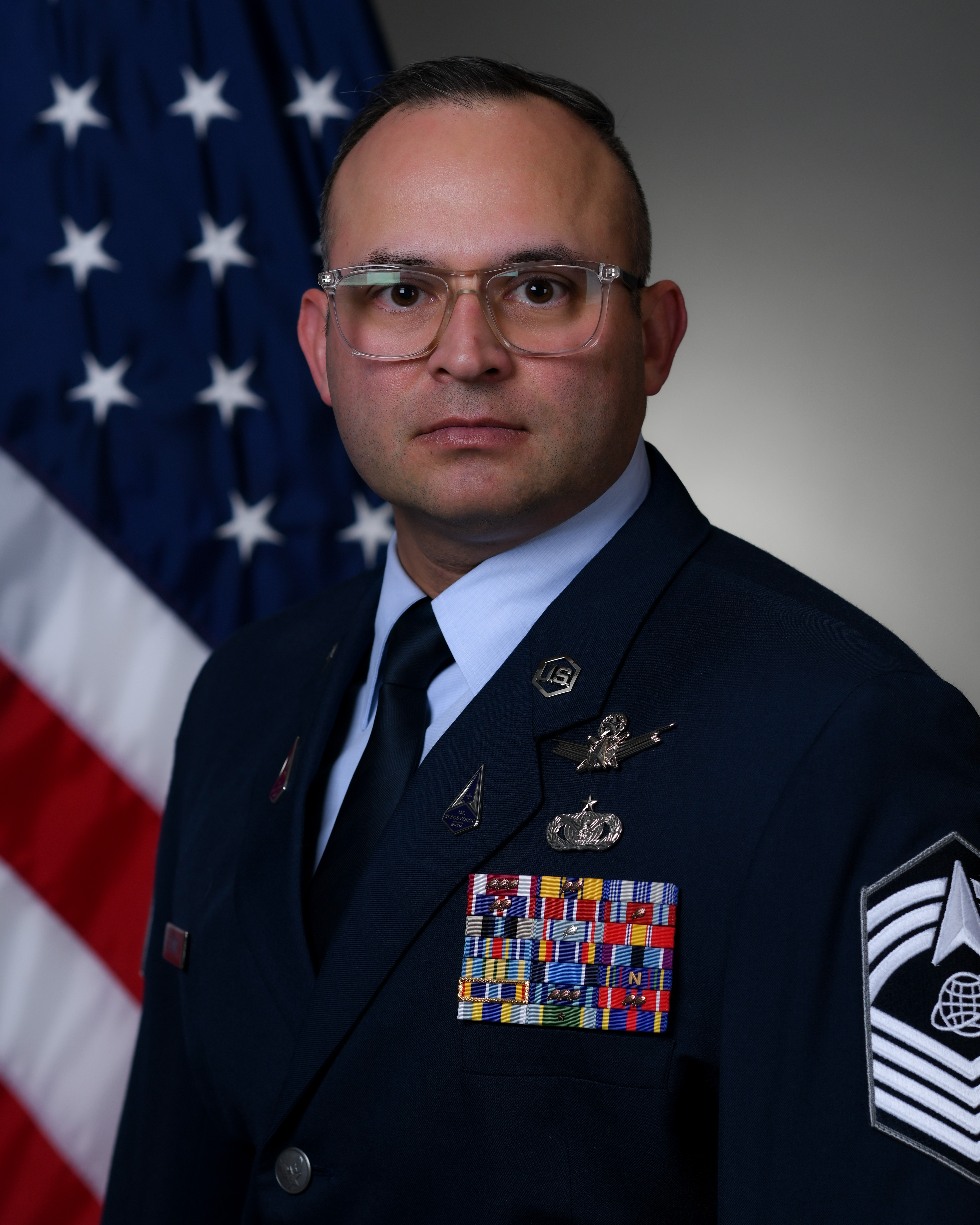 Official photo of  Delta 12 Senior Enlisted Leader SMSgt Matthew Imschweiler with U.S. flag in background