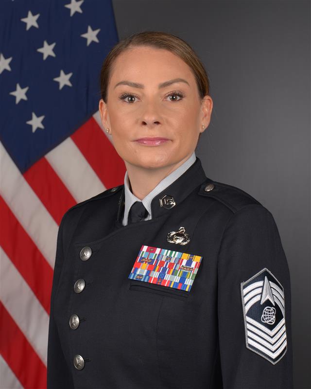 Official photo of  Delta 10 Senior Enlisted Leader CMSgt Andrea Rodriguez with U.S. flag behind him